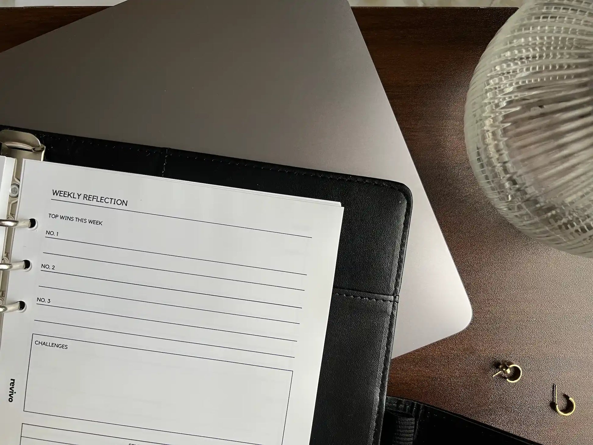 A planner on top of a laptop on a desk