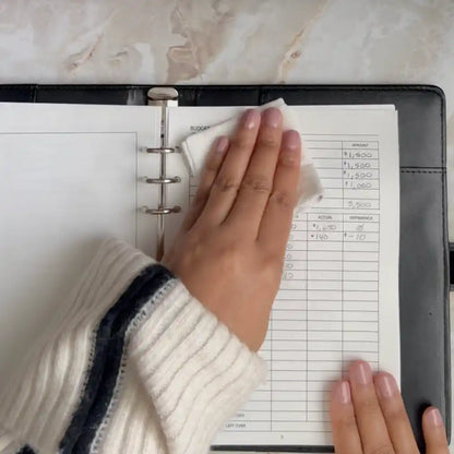 A woman demonstrates how to use reusable planner insert pages from Revivo Planners by wiping away written text with a soft cloth lightly dampened with water.